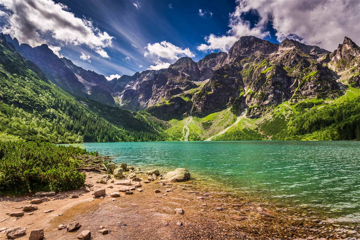 Fototapet o zi de vară lângă un lac înconjurat de munți verzi